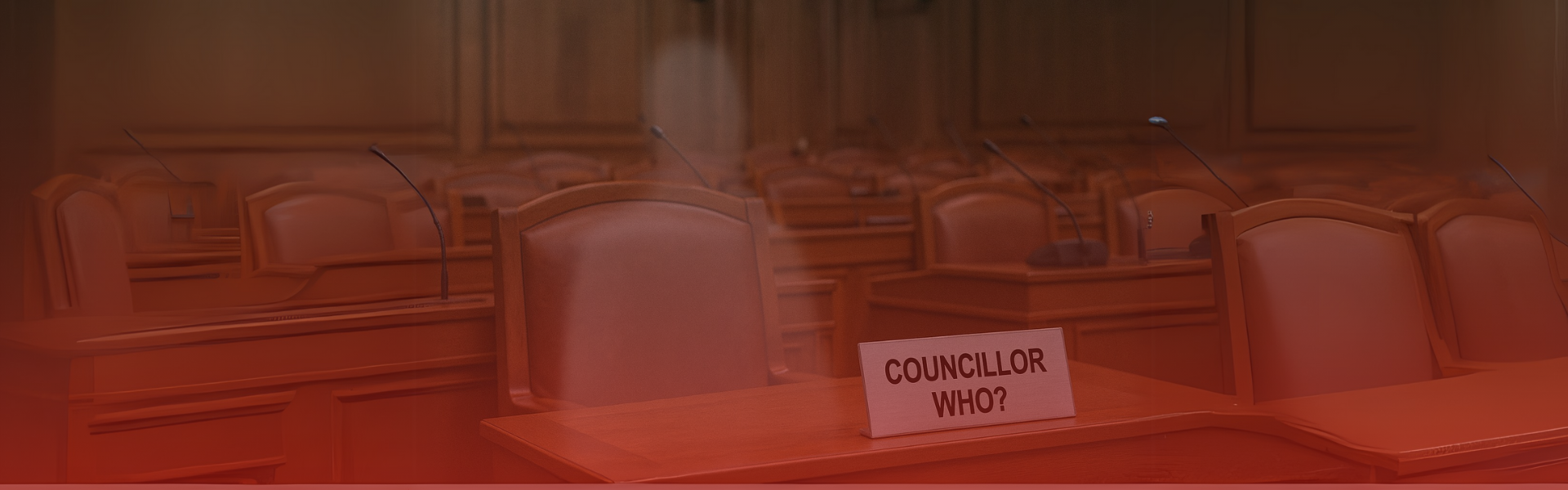 A ghostly figure sits in an empty council chamber